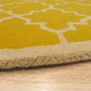 Close-up shows a thick yellow rug with a cream geometric pattern resting on light wood flooring.