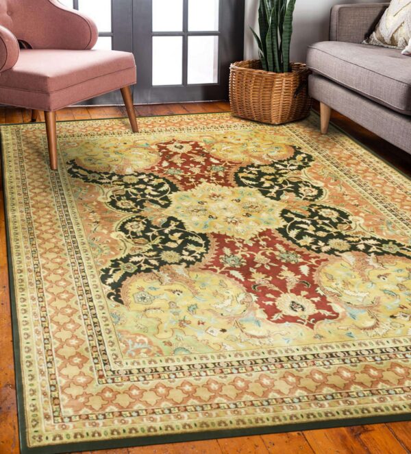 Gold, red, and black ornate traditional rug on wood floor with pink and gray furniture nearby.