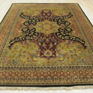 Detailed traditional rug in gold, burgundy, and black floral patterns sits on light wood planks.