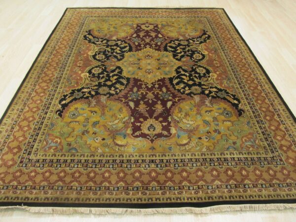 Detailed traditional rug in gold, burgundy, and black floral patterns sits on light wood planks.