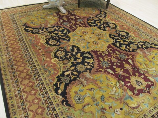 Traditional rug with gold, burgundy, and black floral designs bordered by rust tones on a light floor.
