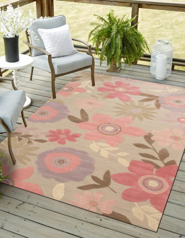 Large pink and purple floral rug on a gray wooden deck near two cushioned patio chairs.