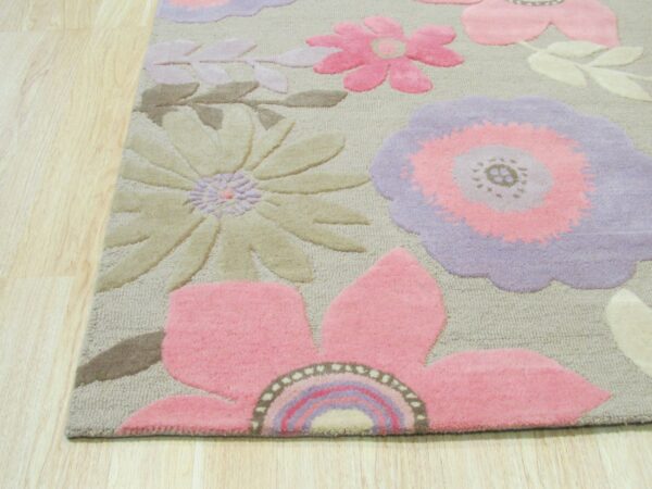 Dimensional rug with large pink, purple, and beige flowers shown against light wood plank flooring.