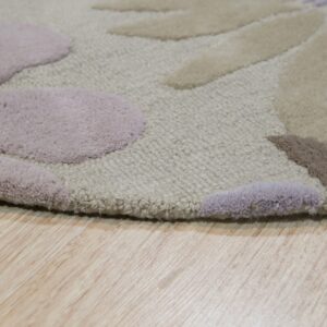 The carved floral rug features varying pile heights in beige, mauve, and brown on wood flooring.