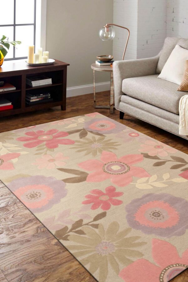 A beige rug featuring large pink, lavender, and brown floral patterns rests on wood flooring beside a gray armchair.