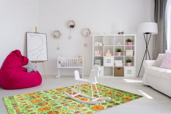 A bright lime green and orange distressed rug sits under a white rocking horse in a modern nursery.