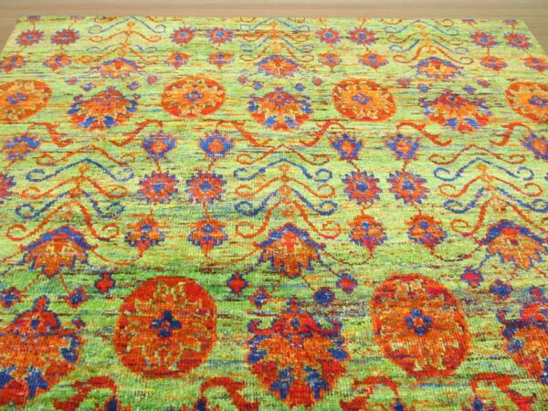 Textured rug in chartreuse green, featuring stylized floral patterns in vibrant orange and blue.