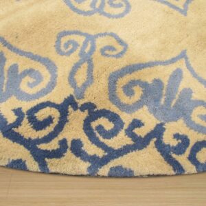 Medium-pile tan rug featuring large, swirling light and dark blue patterns on wood flooring.