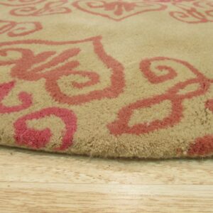 Textured close-up of a beige, medium-pile rug patterned with bold pink scrollwork on light wood floor.