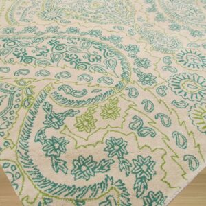 Cream textured rug with a bright teal and lime green paisley and floral pattern on wood floor.