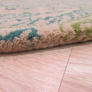 Medium-pile rug detail showing beige, teal, and green pattern on a light wood floor.