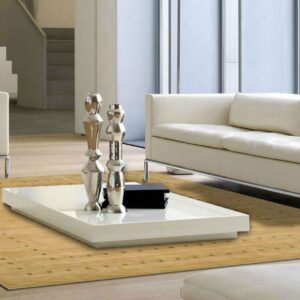 Tan low-pile rug with small dark repeating cross motifs anchors a modern room with cream seating and a white coffee table.