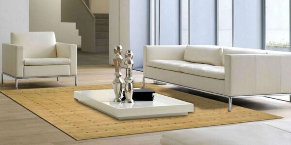 Tan low-pile rug with small dark repeating cross motifs anchors a modern room with cream seating and a white coffee table.