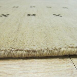 Thick cream rug edge showing dark geometric patterns and pile texture over light wood floor.