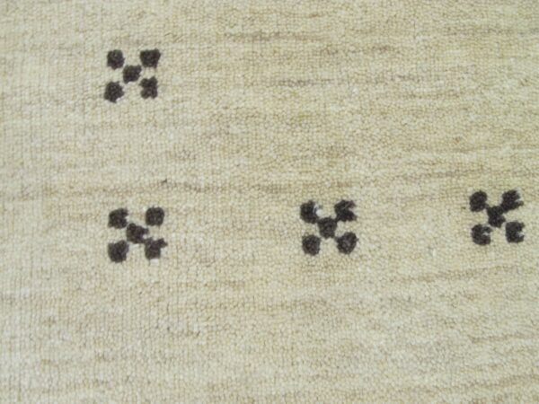 A close-up view of a textured cream rug with scattered dark brown geometric cross motifs.