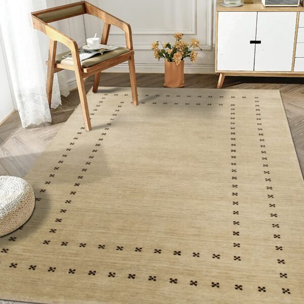 Textured beige rug featuring a dark minimalist dotted border in a sunlit room with wood furniture.