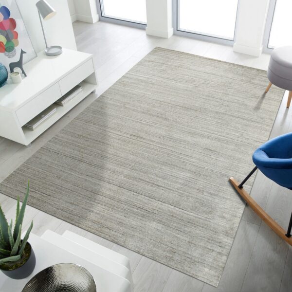 Low-pile heathered gray rug featuring horizontal striations in a brightly lit room with white furniture.