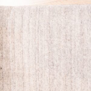 Speckled light beige rug with a textured surface lying on a bright wooden floor.