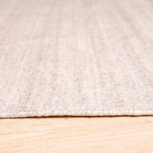 Close-up of a tightly bound light oatmeal rug resting on bright wood plank flooring.