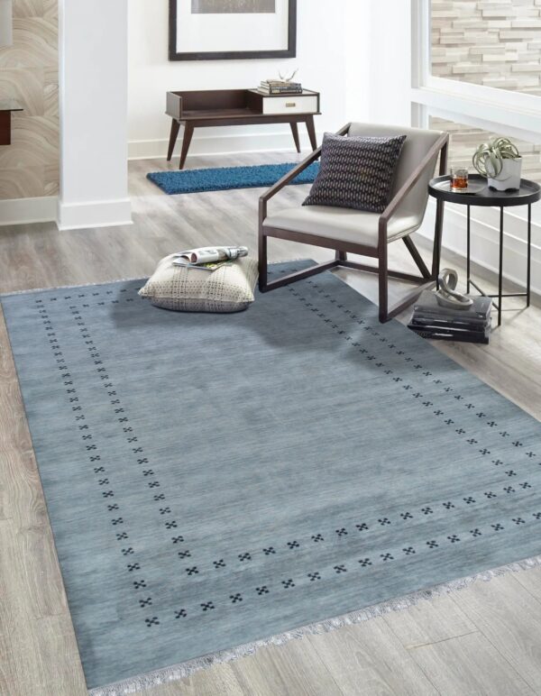 Light blue area rug featuring a repeating dark geometric border anchors a modern seating area.