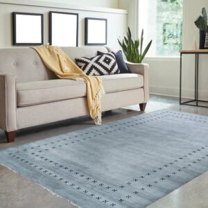 Light blue textured rug with a subtle dark geometric border on concrete next to a neutral sofa.