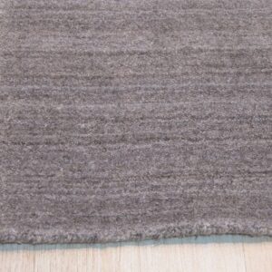 A textured brownish-gray area rug with subtle horizontal striations lies on light wood plank flooring.