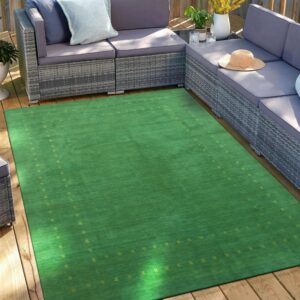 A bright green rug with a subtle yellow border pattern lies on a wooden deck next to a gray sofa.