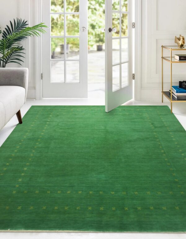 Solid green low-pile rug featuring a subtle yellow-green border in a sunlit white room with french doors.
