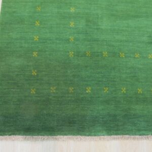 Green low-pile rug featuring scattered yellow quatrefoil patterns and short fringe on pale wood.