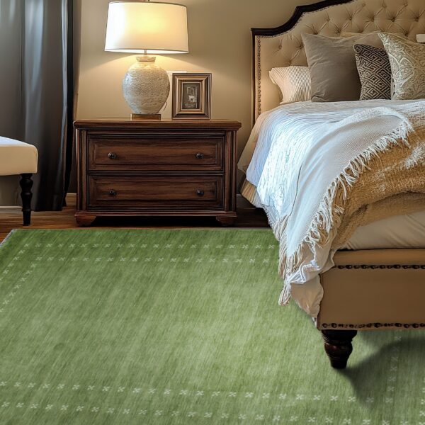Low pile green rug with a subtle patterned border in a warmly lit traditional bedroom setting.