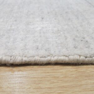 Textured gray and cream rug edge with visible binding rests on a shiny light wood floor.