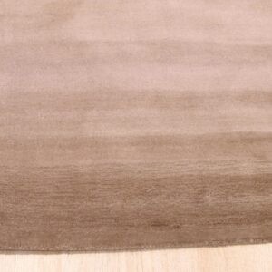 A soft, light brown rug with horizontal color variations rests on natural wood plank flooring.