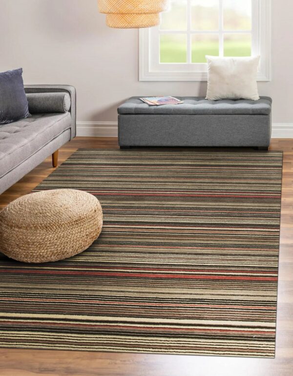 Earth-toned striped rug anchors a living space with a gray sofa and a woven pouf.
