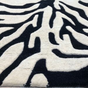 Black and cream rug with carved zebra stripes sits on a light wood floor.