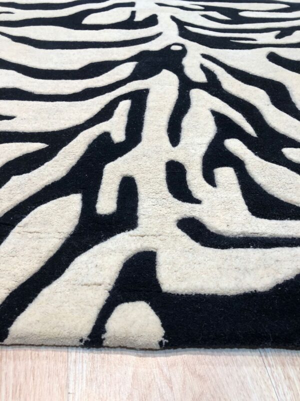 Black and cream rug with carved zebra stripes sits on a light wood floor.