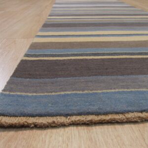 Runner rug with horizontal blue, brown, and cream stripes lies on light wood flooring, showing short fringe.