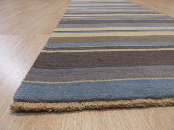 Runner rug with horizontal blue, brown, and cream stripes lies on light wood flooring, showing short fringe.