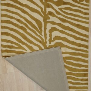 Gold and cream zebra-striped rug on light wood flooring with one corner folded, showing the backing.