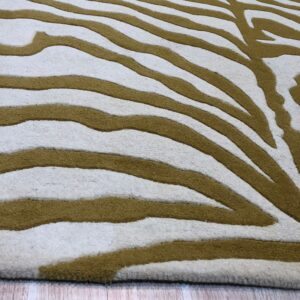Cream rug with carved olive-brown zebra stripes resting on pale wood planks.