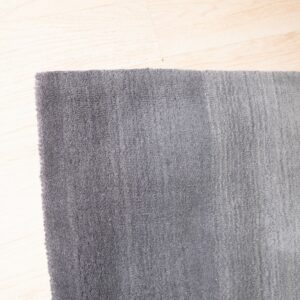 Detailed view of a dense gray rug with visible vertical texture on light blonde flooring.
