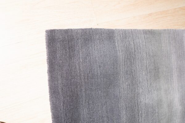 Detailed view of a dense gray rug with visible vertical texture on light blonde flooring.