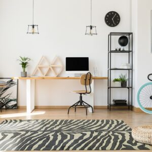 A zebra patterned black and cream area rug grounds a modern home office space on wood flooring.