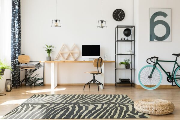 A zebra patterned black and cream area rug grounds a modern home office space on wood flooring.