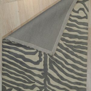 Gray and cream striped rug on light wood floor, corner folded back to show gray backing.