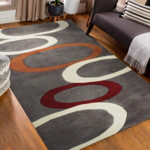 Gray rug with abstract white, rust, and red loops on wood flooring near a dark couch.