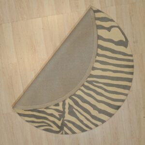 Round zebra-striped rug, cream and gray, folded to reveal the fabric backing on a light wood floor.