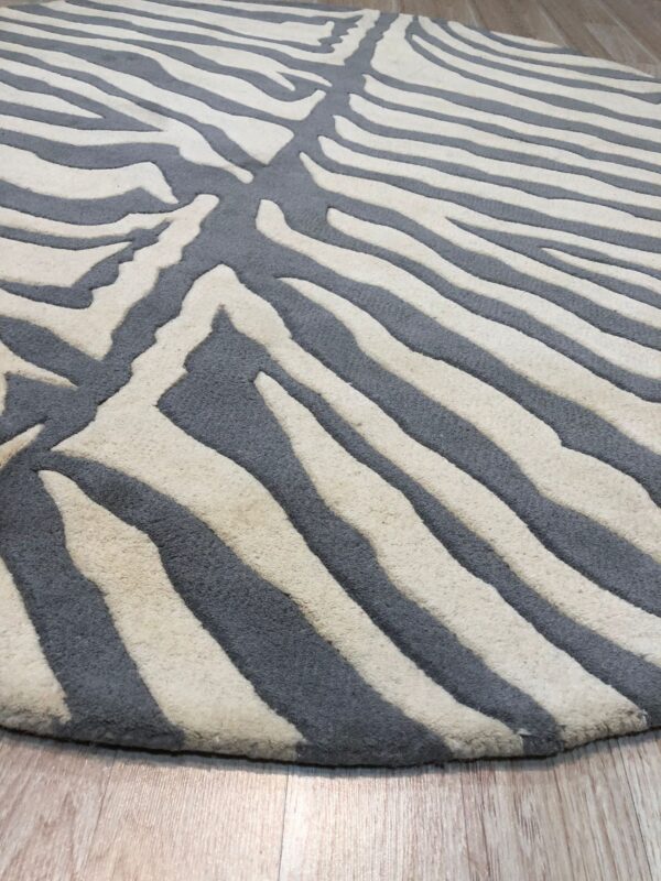 Close view of a plush gray and cream zebra pattern rug on light brown wood flooring.