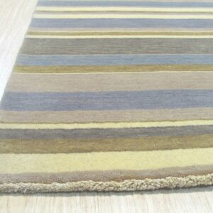 A striped rug with muted blue, gray, gold, and cream colors lies on light plank flooring.