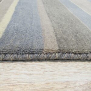 Striped rug in shades of blue, gray, and cream, showing the edge and medium pile on a light wood floor.