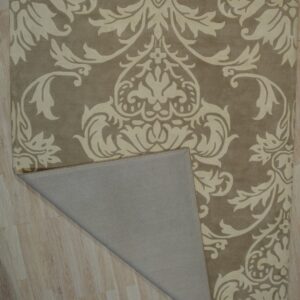 Beige rug with high-contrast light damask pattern lying on wood flooring, showing the folded gray backing.